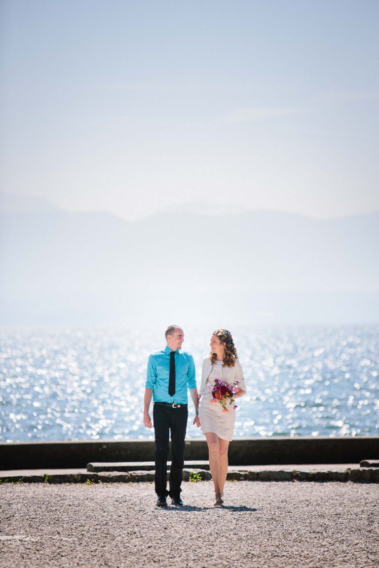 Bride & groom walk by shimmering lake in Rolle.