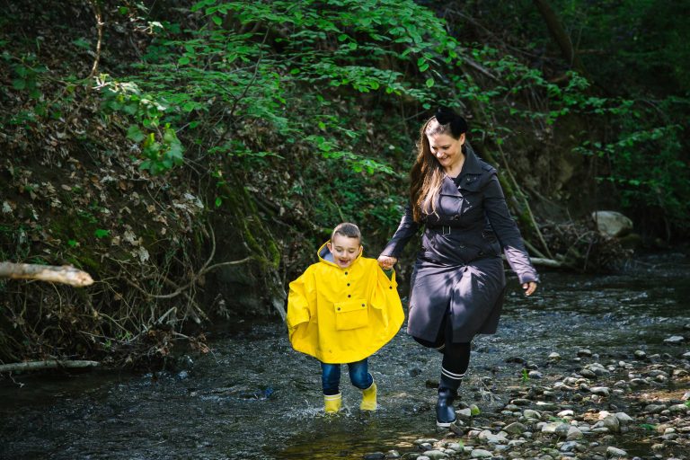 Mother and son run in stream in their wellies.