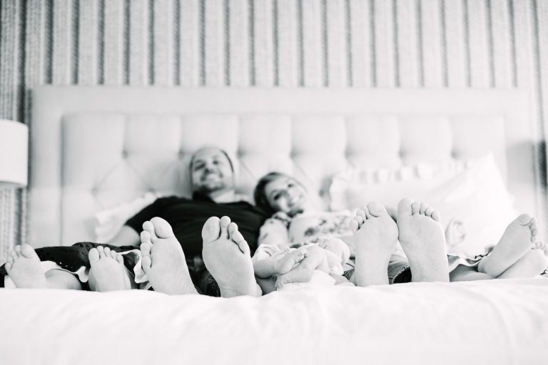 Family of five with newborn on bed feet
