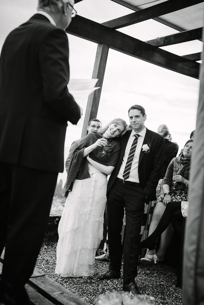 Bride and groom listen to the father of the bride's speech together